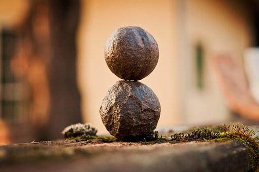 balanced stone ball sculpture on mossy surface